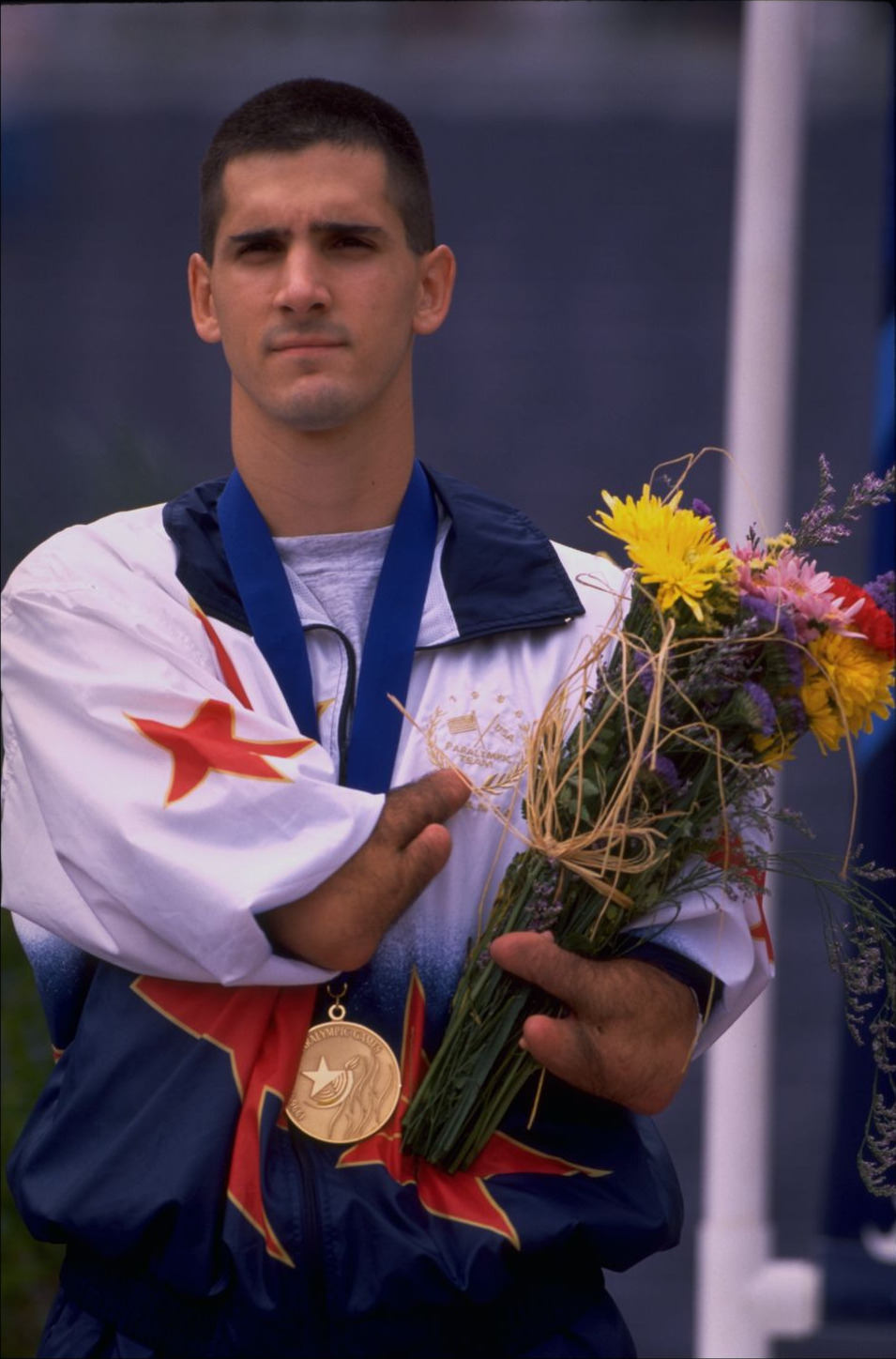 Tony Volpentest looking straight ahead with medal and bouquet
