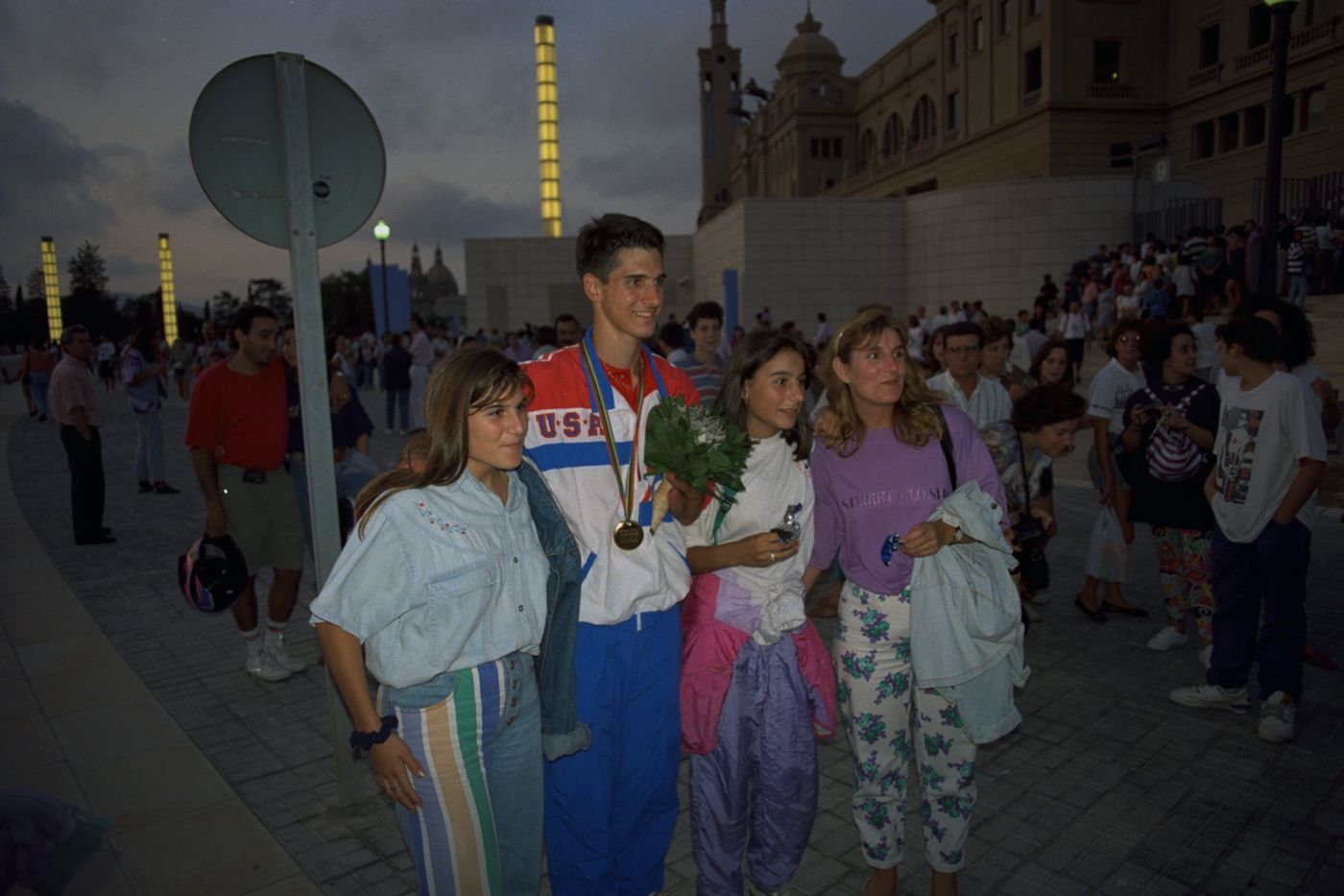 Tony Volpentest in a USA tracksuit, wearing a medal, photographed with three children outside the stadium, Barcelona 1992
