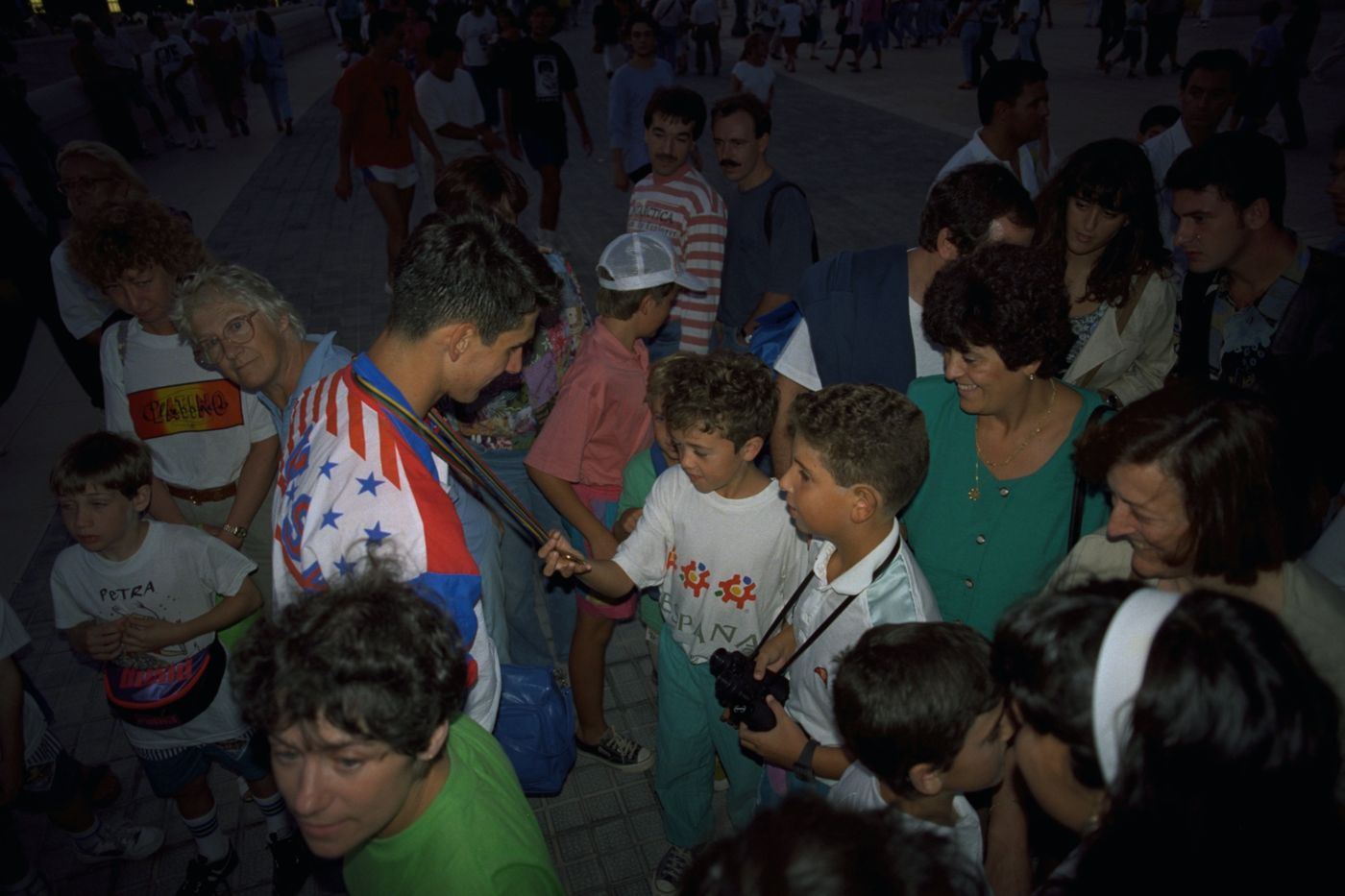 Tony Volpentest showing his medal to two boys in a crowd outside the stadium, Barcelona 1992