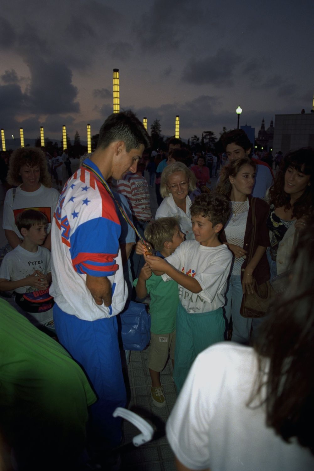 Tony Volpentest letting two boys hold his medal at dusk outside the stadium, Barcelona 1992