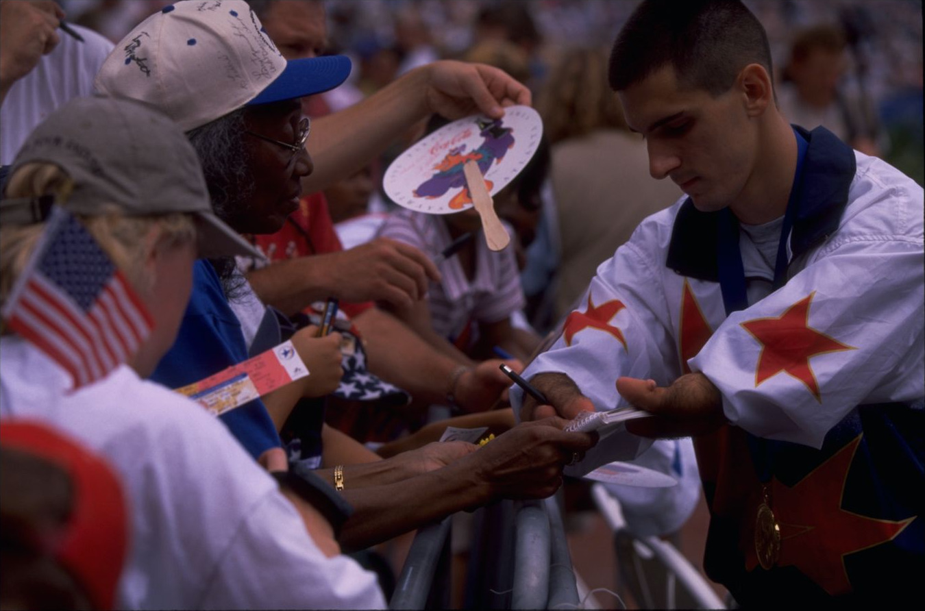 Tony Volpentest signing autographs for a line of spectators reaching over the rail
