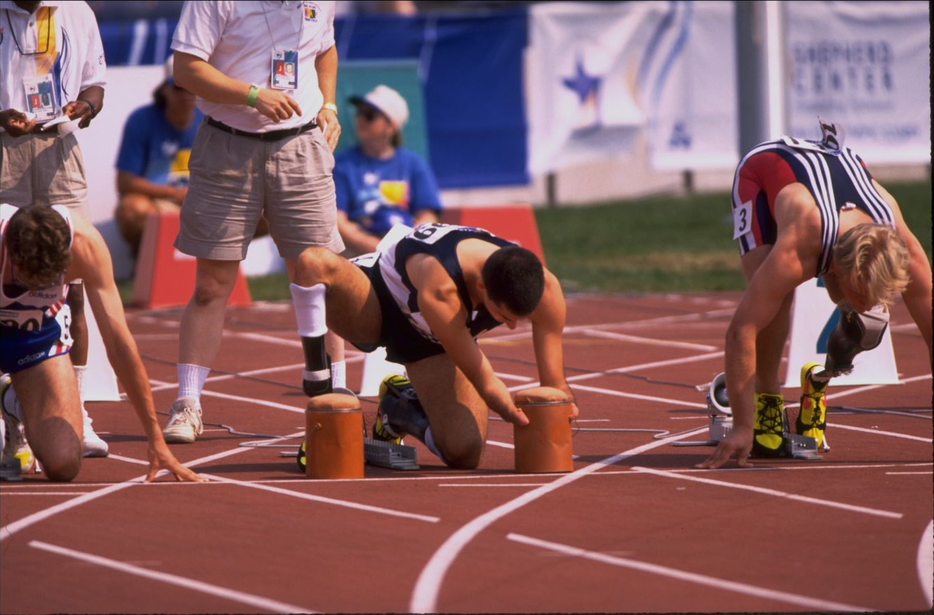 Sprinters crouched at the start line, Tony Volpentest resting his forearms on the starting supports