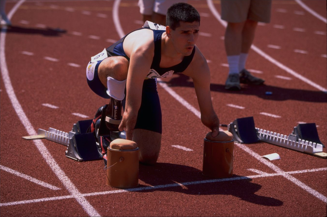 Tony Volpentest in the set position, forearms on the padded starting supports, looking down the track
